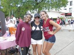 Three students posing for a picture in their Greek gear in the quad.