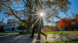 two students walking on campus backlit by the sun