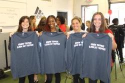 A photo of 4 Montclair State students holding up t-shirts that read "Support women, support the world"